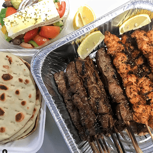 Large Greek sharing platter with mixed grilled meats, pita bread, salads and traditional sides